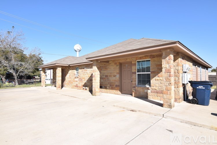 A house with a brown roof and a blue trash bin in front.