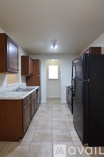 A kitchen with black appliances and brown cabinets.