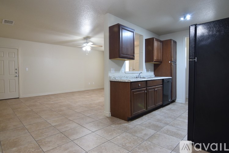A kitchen with brown cabinets and a black refrigerator.