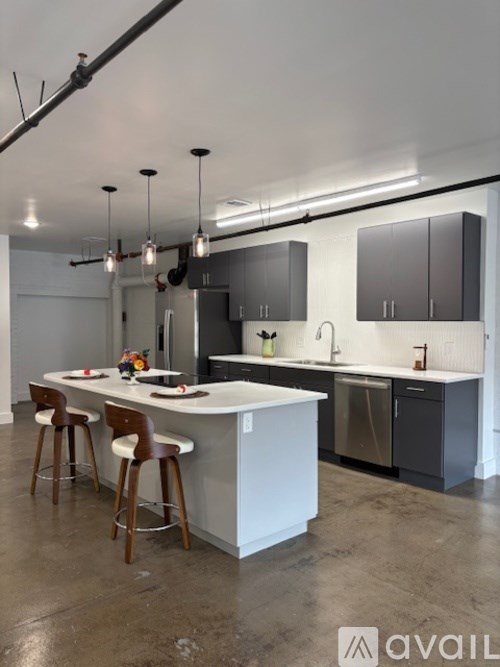 A modern kitchen with a white island and dark brown bar stools.