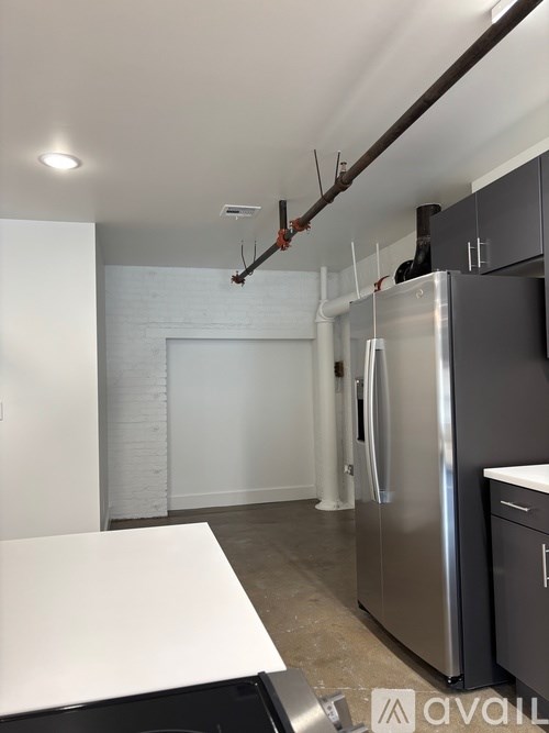 A kitchen with a white counter top and a stainless steel refrigerator.