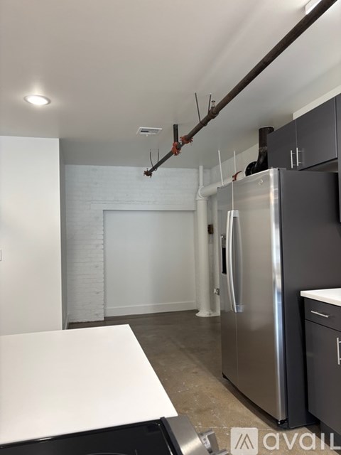 A kitchen with a white counter top and a stainless steel refrigerator.