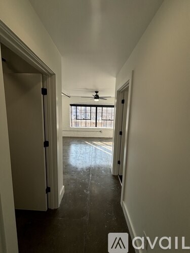 A long hallway with a fan and a window.