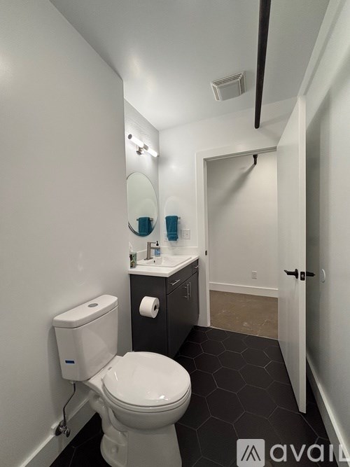 A bathroom with a toilet, sink, mirror, and a door.