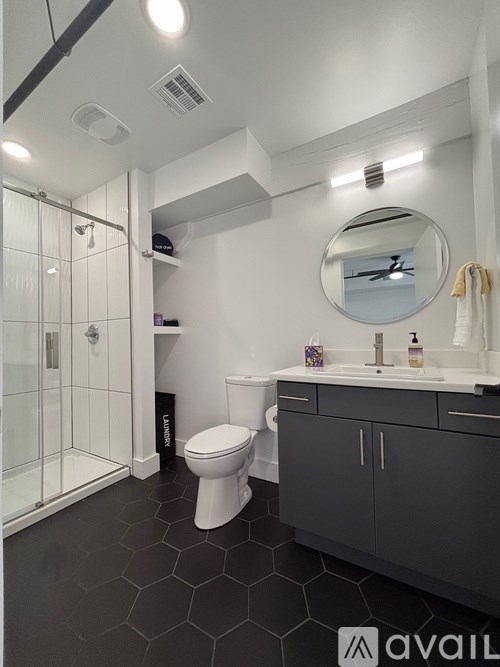 A bathroom with a toilet, sink, mirror, and a glass shower stall.