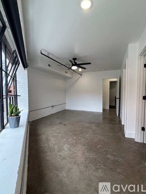 A room with a ceiling fan and a plant on the windowsill.
