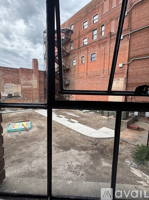 A view from inside a building looking out to a courtyard with a brick building in the background.