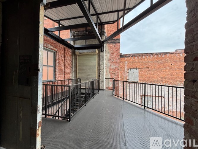 A balcony with a metal railing and a brick wall.