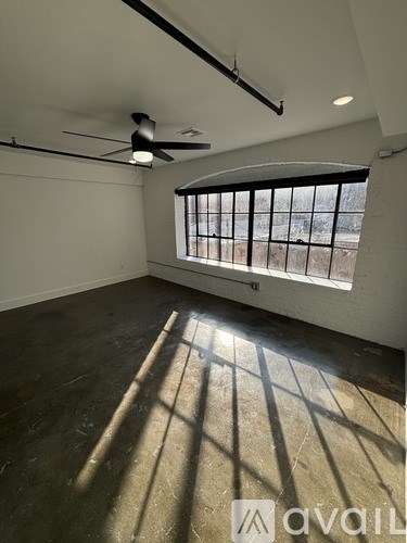A room with a fan and a window letting in sunlight.