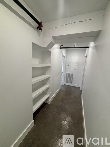 A hallway with white walls and a black floor.
