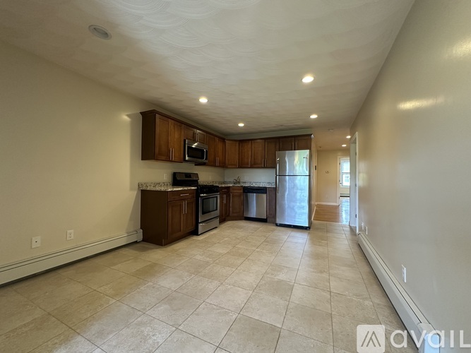 A spacious living room with a kitchen area in the background.