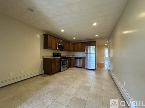 A spacious living room with a kitchen area in the background.