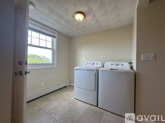 A room with two washing machines and a window.