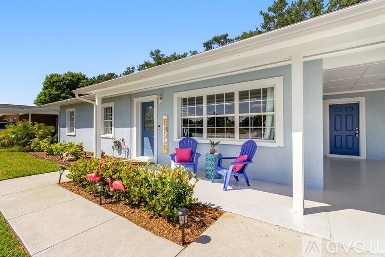A white house with blue doors and windows has a small garden in front.