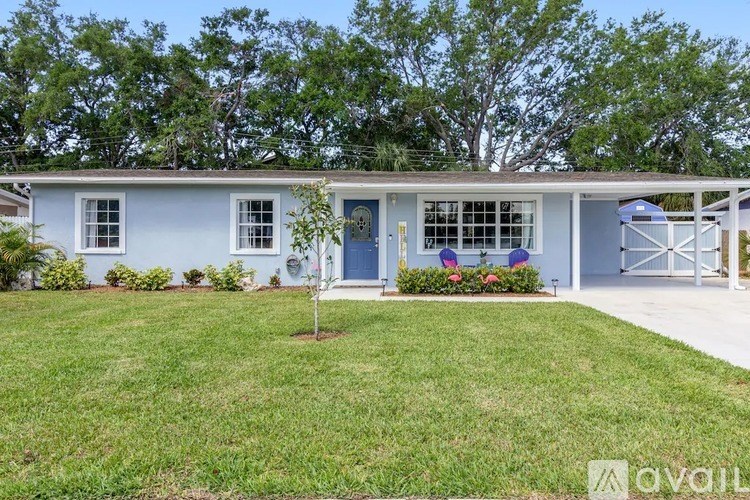 A blue house with a white fence and a small tree in front.