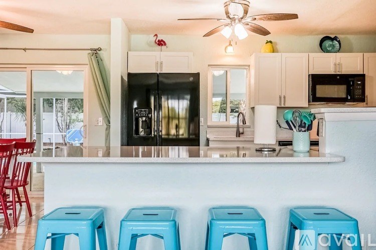 A kitchen with a white counter and blue stools.
