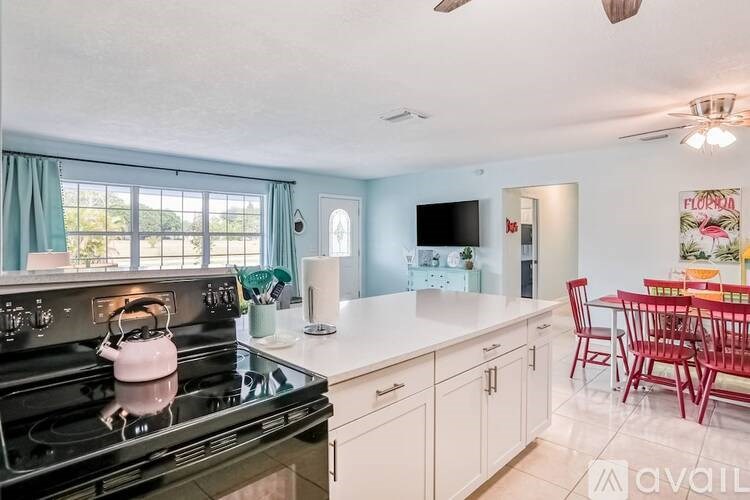 A kitchen with a black stove top and a red dining table.