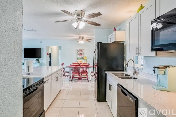 A kitchen with a black refrigerator and a dining table with chairs.