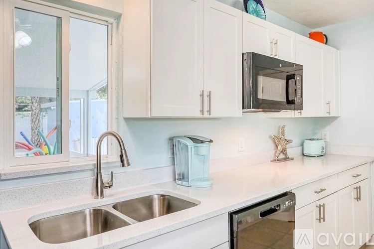 A kitchen with a sink, microwave, and toaster oven.