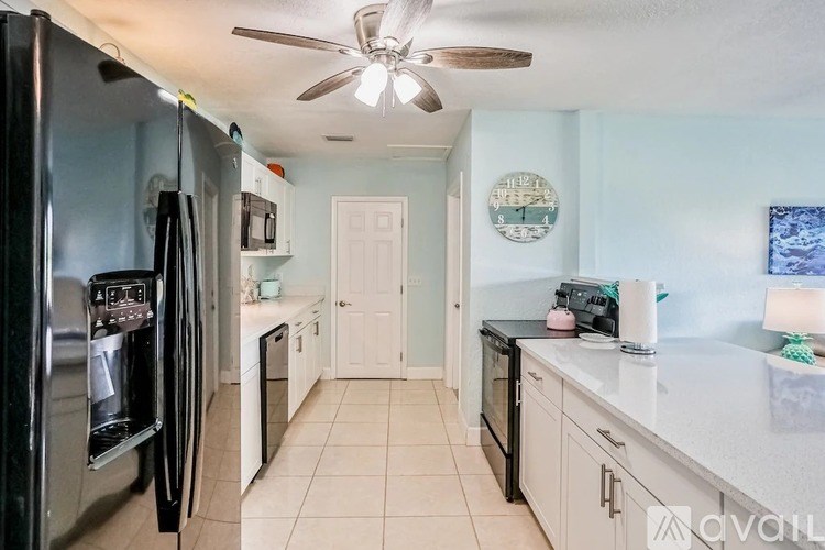 A kitchen with a black refrigerator and white cabinets.
