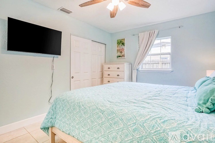 A bedroom with a bed, dresser, and a ceiling fan.