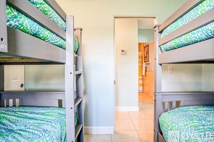 A room with two bunk beds and a doorway leading to another room.