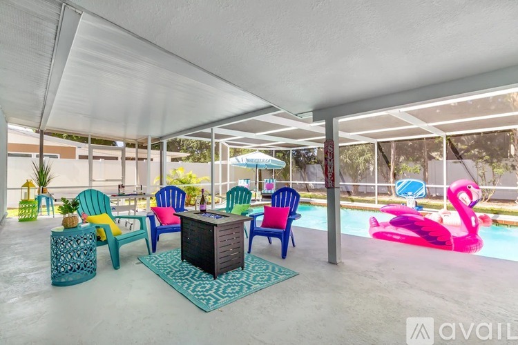 A patio with a pool and a pink flamingo float.