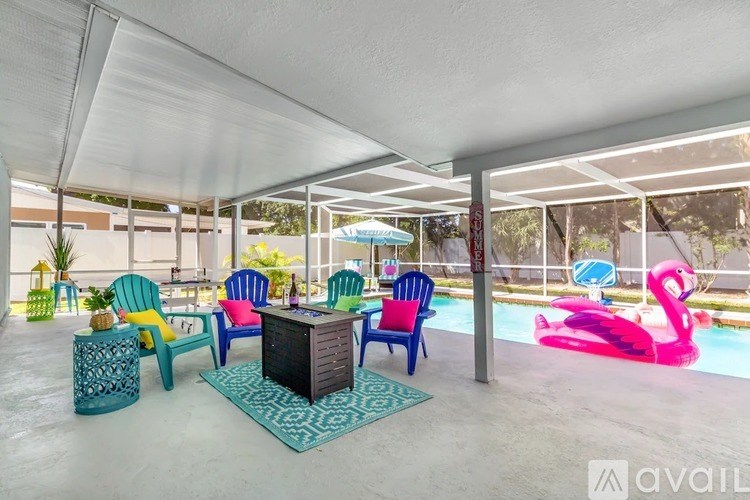 A patio with a pool and a pink flamingo float.
