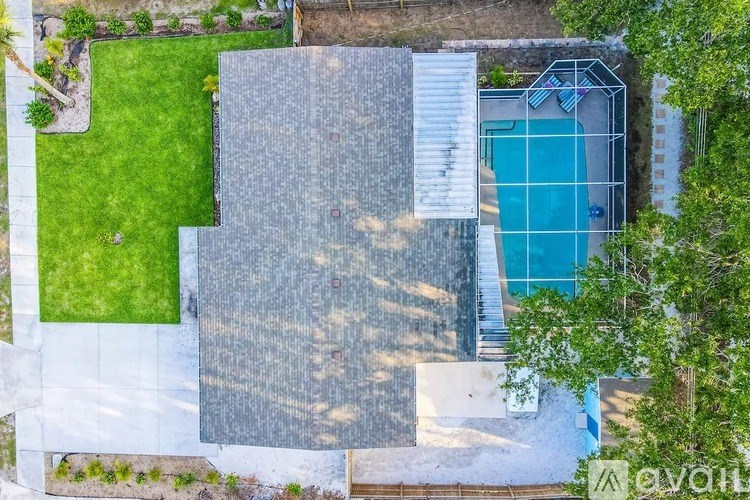 A swimming pool surrounded by a stone wall and a green lawn.