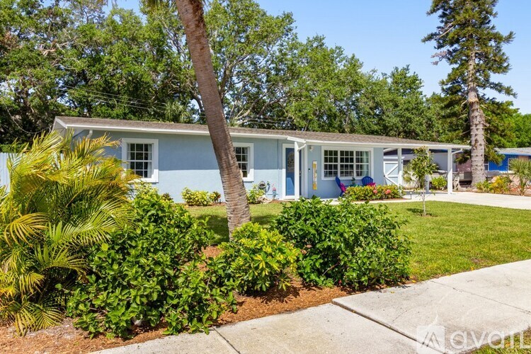 A blue house with a white fence and green bushes in front.