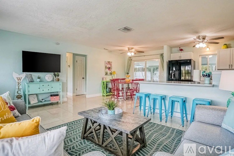 A living room with a grey couch, a coffee table, and a bar area with stools.