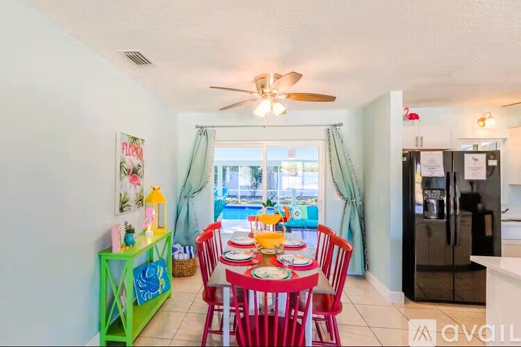 A dining room with a red table and chairs.