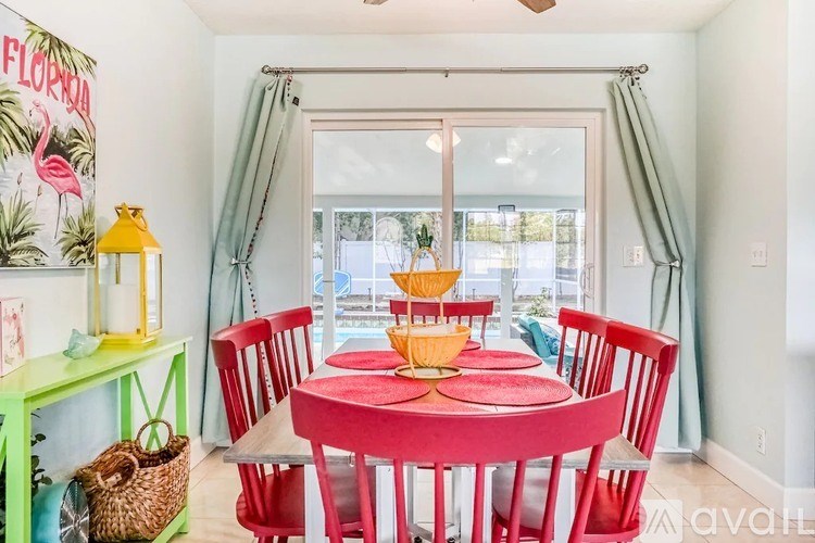 A dining room with a red table and chairs.