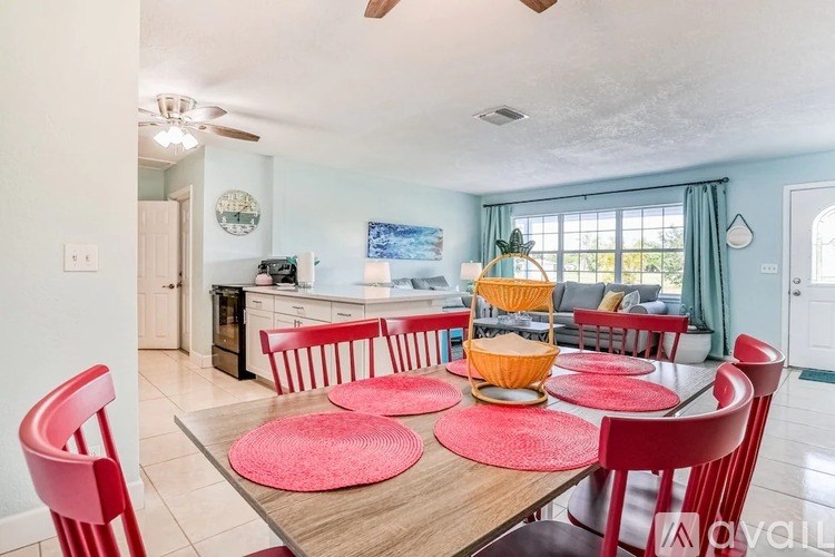 A dining room with a table set for six with red chairs.