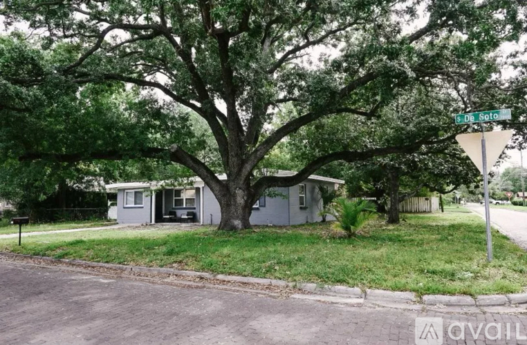 A tree in front of a house with a street sign that says 18th St.