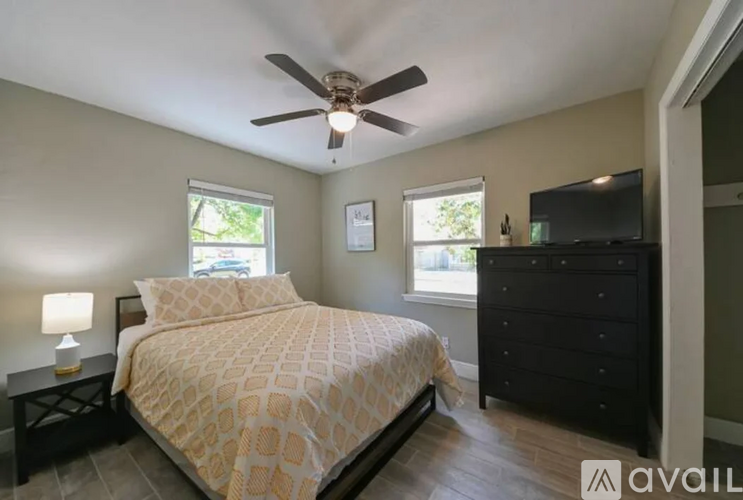 A bedroom with a bed, dresser, and ceiling fan.