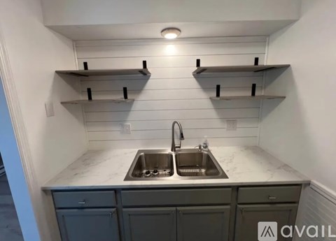 A kitchen with a sink and shelves above it.