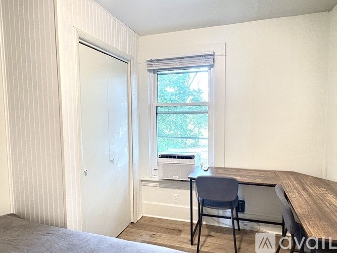 A room with a desk and chair in front of a window.