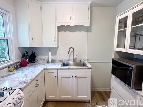 A kitchen with white cabinets and a marble countertop.