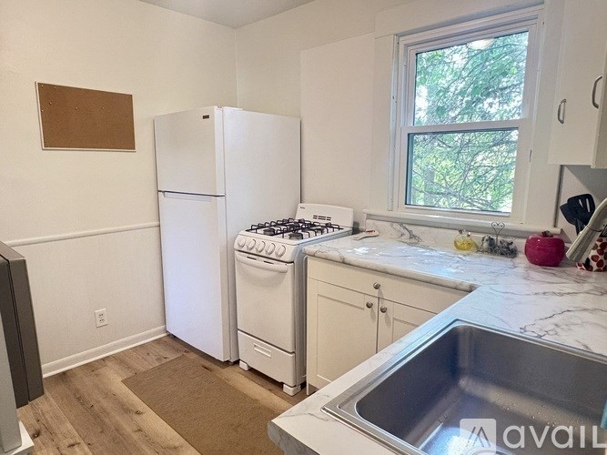 A kitchen with a white refrigerator, stove, and sink.