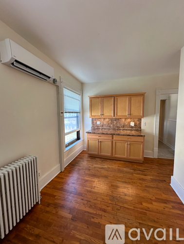 A room with wooden floors and a window with blinds.