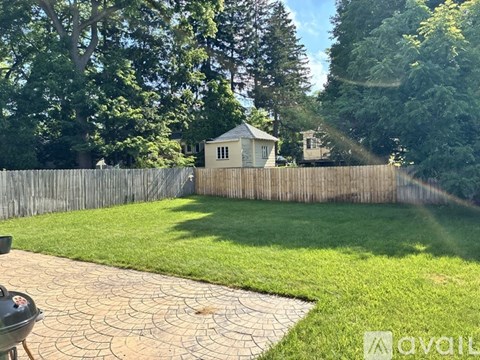 A backyard with a BBQ grill and a wooden fence.