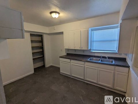 A kitchen with white cabinets and a black countertop is available for rent.