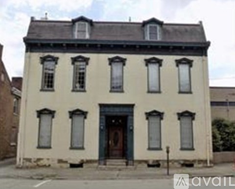 A white building with a black roof and a blue door.
