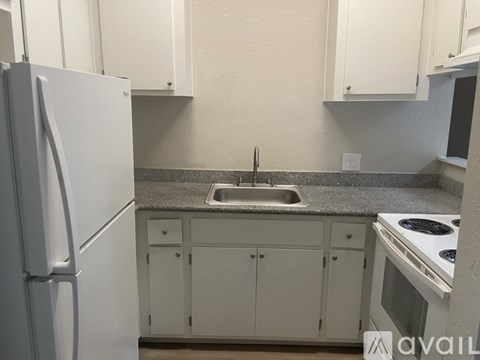A kitchen with white cabinets and a white refrigerator.