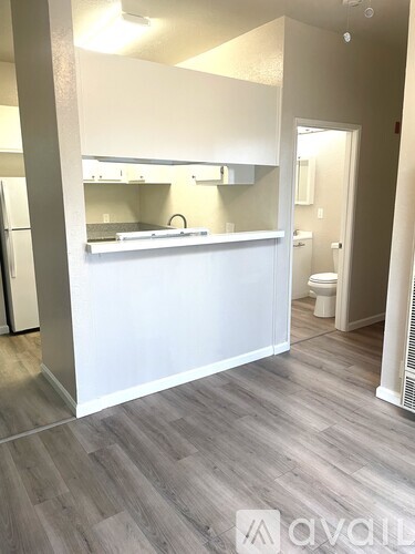 A kitchen with white cabinets and a wooden floor.