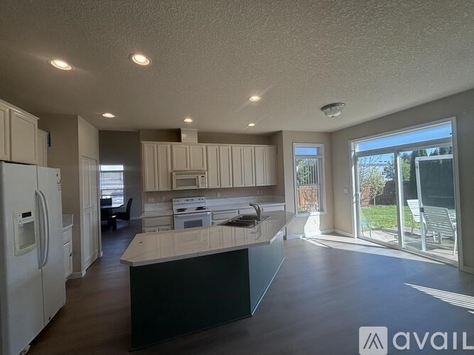 A kitchen with white appliances and a large island.