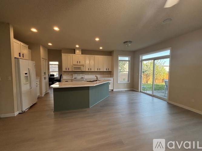 A kitchen with a green island and wooden floors.
