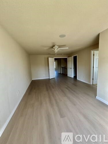 A long, empty hallway with a fan on the ceiling.