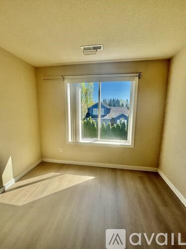 A room with a window showing a house and trees outside.